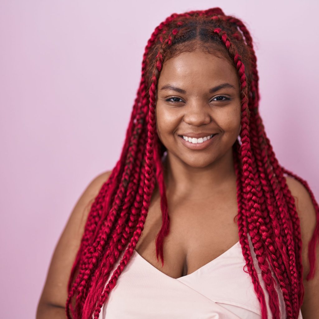 African american woman with braided hair standing over pink background hands together and fingers crossed smiling relaxed and cheerful. success and optimistic