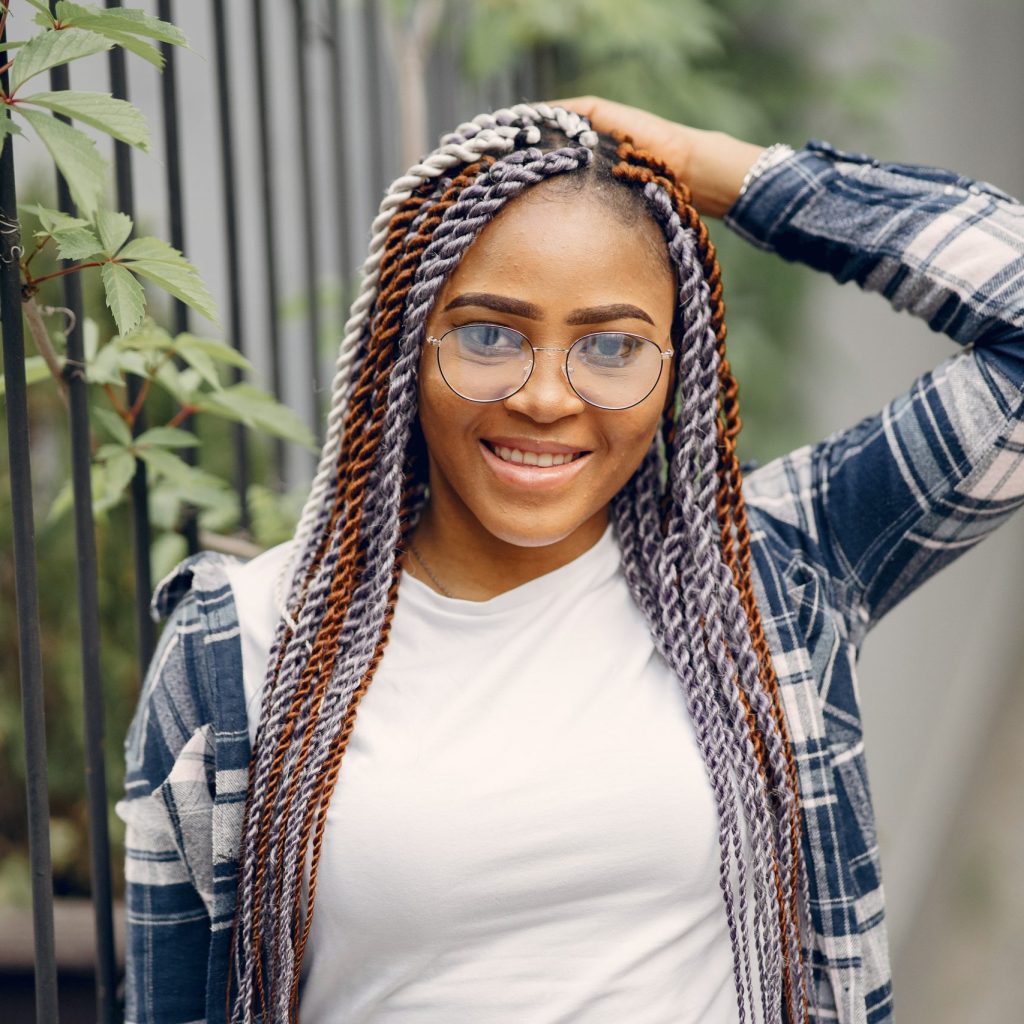 Young black woman with afro hairstyle smiling in urban park. Mixed girl walking in a city.